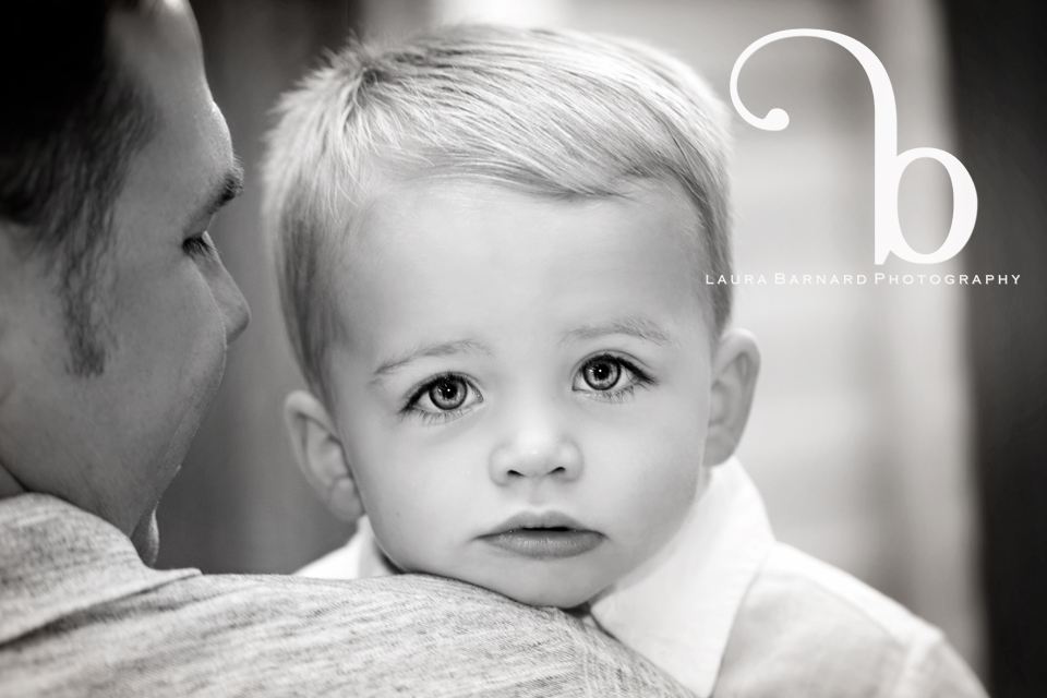 A toddler resting on a parent's shoulder, black and white.