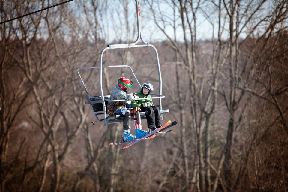 Two children mid-air on a ski lift.