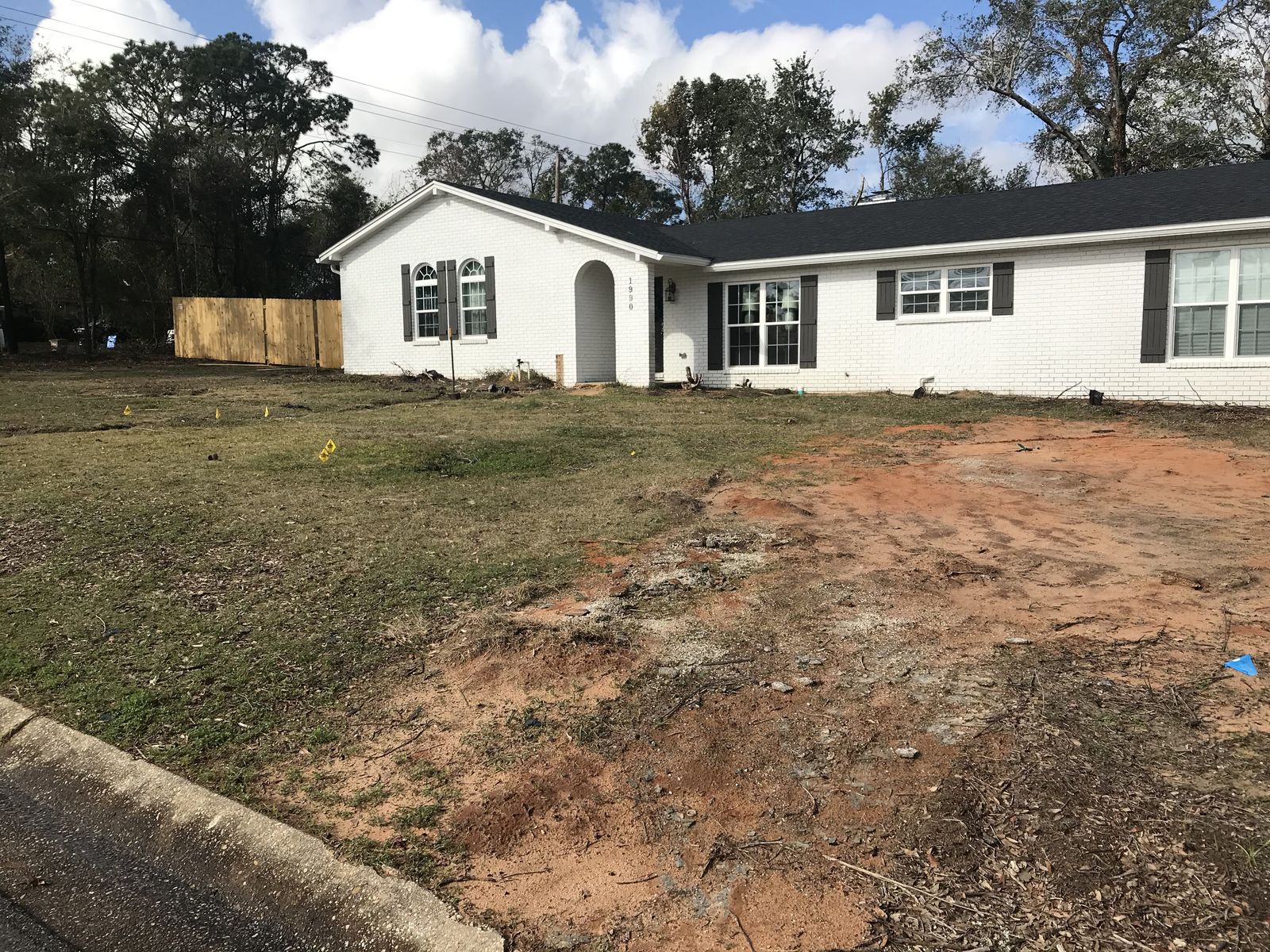 Before: a front yard of bare red dirt and patchy grass in front of a white brick ranch house